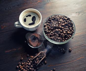Still life with coffee cup, roasted coffee beans and ground powder on vintage wooden background.
