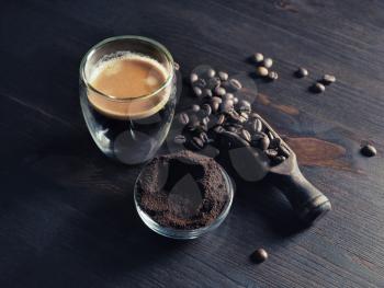 Espresso on wood kitchen table background. Coffee cup, roasted coffee beans and ground powder.