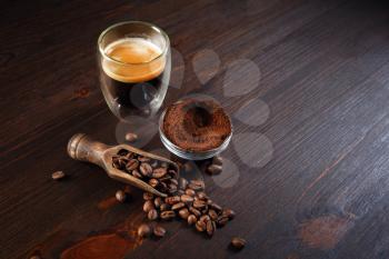 Still life with coffee espresso cup, roasted coffee beans and ground powder on wooden background. Copy space for your text.