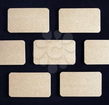 Brown paper business cards mockup on black wooden background. Template for ID. Flat lay.