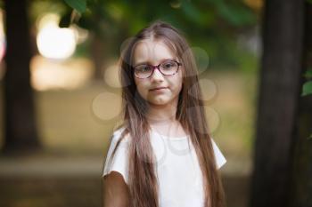 Child girl with long hair outdoors. Schoolgirl with glasses. Selective focus.