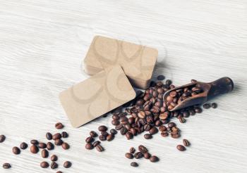 Coffee beans and kraft paper business cards over light wood table background.