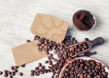 Photo of blank vintage business cards, coffee beans and ground powder on light wood table background. Flat lay.