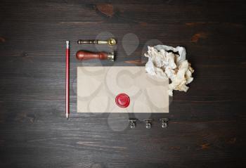 Vintage blank envelope with wax seal, stamp, pencil, spoon and crumpled paper on wood table background. Top view. Flat lay.