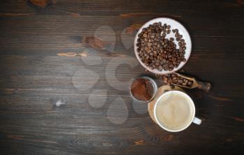 Photo of coffee cup, roasted coffee beans and ground powder on wooden table background. Copy space for your text. Top view. Flat lay.
