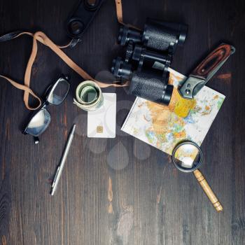Photo of travel accessories on vintage wood table background. Top view of personal traveler's items. Flat lay.