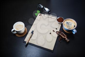 Blank stationery and coffee on black table background. Branding mock-up.