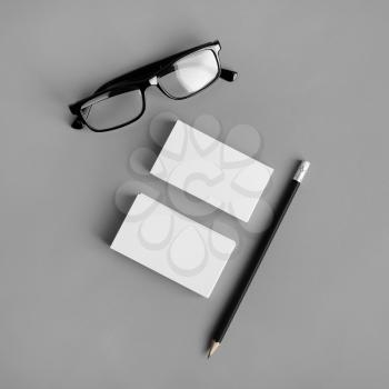 Blank stationery template on gray paper background. Business cards, pencil and glasses. For design presentations and portfolios. Flat lay.