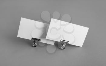 Blank white business cards and metal binder clips on gray background. Mockup for branding identity.