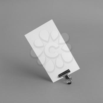 Photo of blank paper business card and binder clip on gray paper background. Mockup for branding identity.