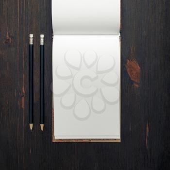 Blank open notebook or brochure and pencils on wood table background. Responsive design mockup. Top view. Flat lay.