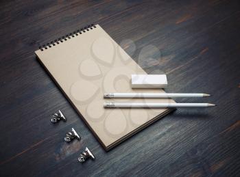 Photo of closed blank kraft notebook, pencil and eraser on wooden background. Stationery template.