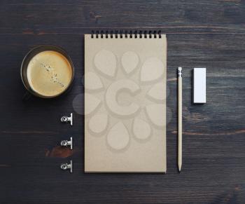 Photo of blank kraft sketchbook, pencil, eraser and coffee cup on wooden table background.Top view. Flat lay.