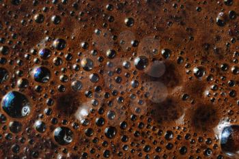 Closeup of coffee foam background. Macro texture of brown coffee foam.