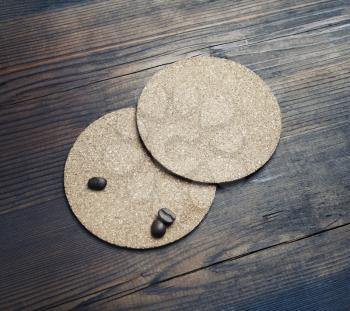 Photo of two blank cork beer coasters and coffee beans on wood table background.