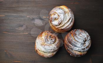 Three delicious sweet buns on wooden background. Flat lay.