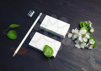 Photo of blank white business cards, pencil, sharpener and spring flowers on wood table background. Branding mock up.