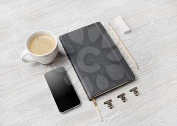 Corporate stationery template. Blank sketchbook, smartphone, pencil, eraser and coffee cup on light wood table background.