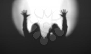Black and white couple silhouettes with hands up in light of floodlight backdrop