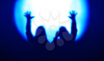 Blue couple silhouettes with hands up in light of floodlight backdrop hd