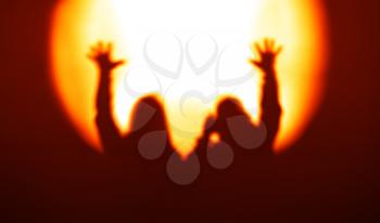 Orange couple silhouettes with hands up in light of floodlight backdrop hd