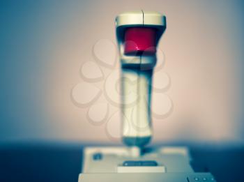 Retro arcade joystick with red button bokeh background