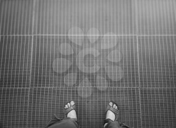 Man in sandals standing on metal grid background
