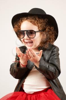 Little girl with black hat and Sunglasses sitting and laughing