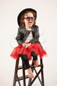 Little girl with black hat and sunglasses sitting on a high stool and dabbles