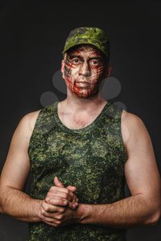 Portrait of Brutal Man with Creative Military Style Camouflage. Face Paint.  Close up on black background