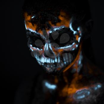 Girl's Face painted in fluorescent UV colors and looks like Neon Glowing Skull