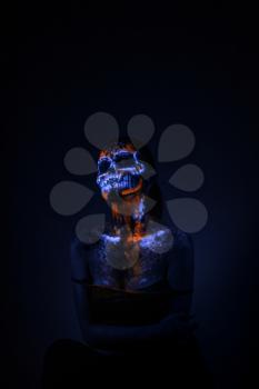 Girl's Face painted in fluorescent UV colors and looks like Neon Glowing Skull