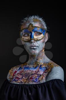 Portrait of a young masked woman with creative makeup on the theme of Venice Carnival