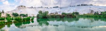Pamukkale, Turkey – 07.15.2019. White mountain and green lake in Pamukkale. Panoramic view from the side of the village on a summer morning