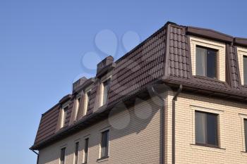 The house with plastic windows and a roof of corrugated sheet. Roofing of metal profile wavy shape on the house with plastic windows.