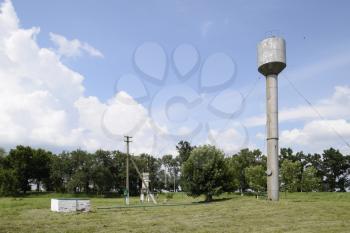 Silver Water Tower among green grass and trees.