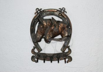 Clothes hanger decorated with the image of a horseshoe and the heads of horses.