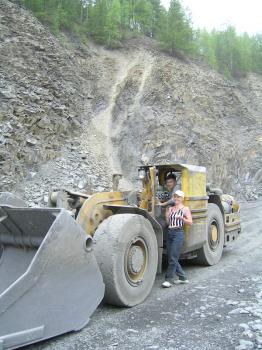 Woman near the grader driver. A woman posing for a photograph next to greder driver.