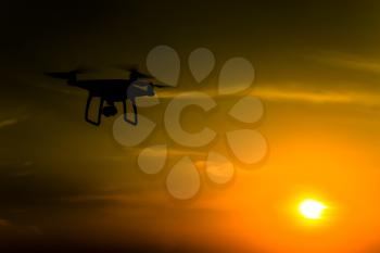 Quadrocopters silhouette against the background of the sunset. Flying drones in the evening sky.