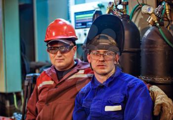 Workers fitters and welders in protective clothing and a helmet. Working in the operating industrial facilities.
