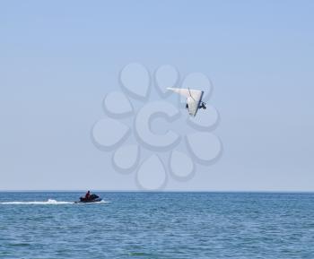 hang-gliding with the motor flies past a water scooter. Trike, flying in the sky with two people. Extreme Entertainment travelers.