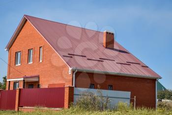 Detached house with a roof made of steel sheets. Roof metal sheets. Modern types of roofing materials.