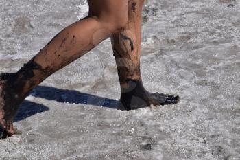 Legs walking girl on the dry bottom of a salt lake. Walking woman on the bottom of a dry lake with salt and mud. The ancient dried-up lake.