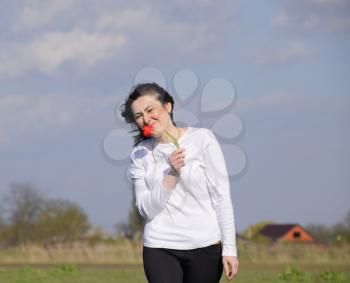 A girl in a white sweatshirt smells a tulip flower.