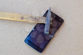 Hammer and smartphone. The screen of the smartphone, a broken hammer. The destruction of the phone.