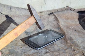 Hammer and smartphone. The screen of the smartphone, a broken hammer. The destruction of the phone.