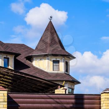 Decorative metal on the roof of a brick house. Fence made of corrugated metal