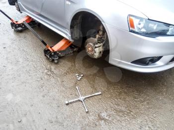 The car is at the tire shop. Under the jack the car in car-care center. The car with the removed wheel