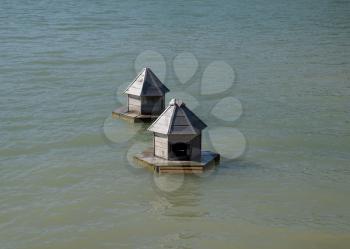 Houses for ducks on the lake. Taking care of ducks. Man-made nests for gray ducks.