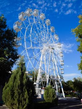 White ferris wheel against the blue sky. Ferris wheel in the park.